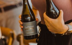 A bottle of LA FRENZ Chardonnay being held ready to pour.