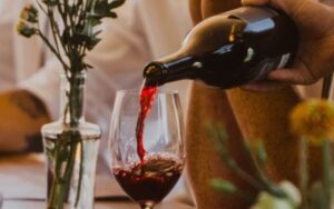 Bottle of red wine being poured into a glass.